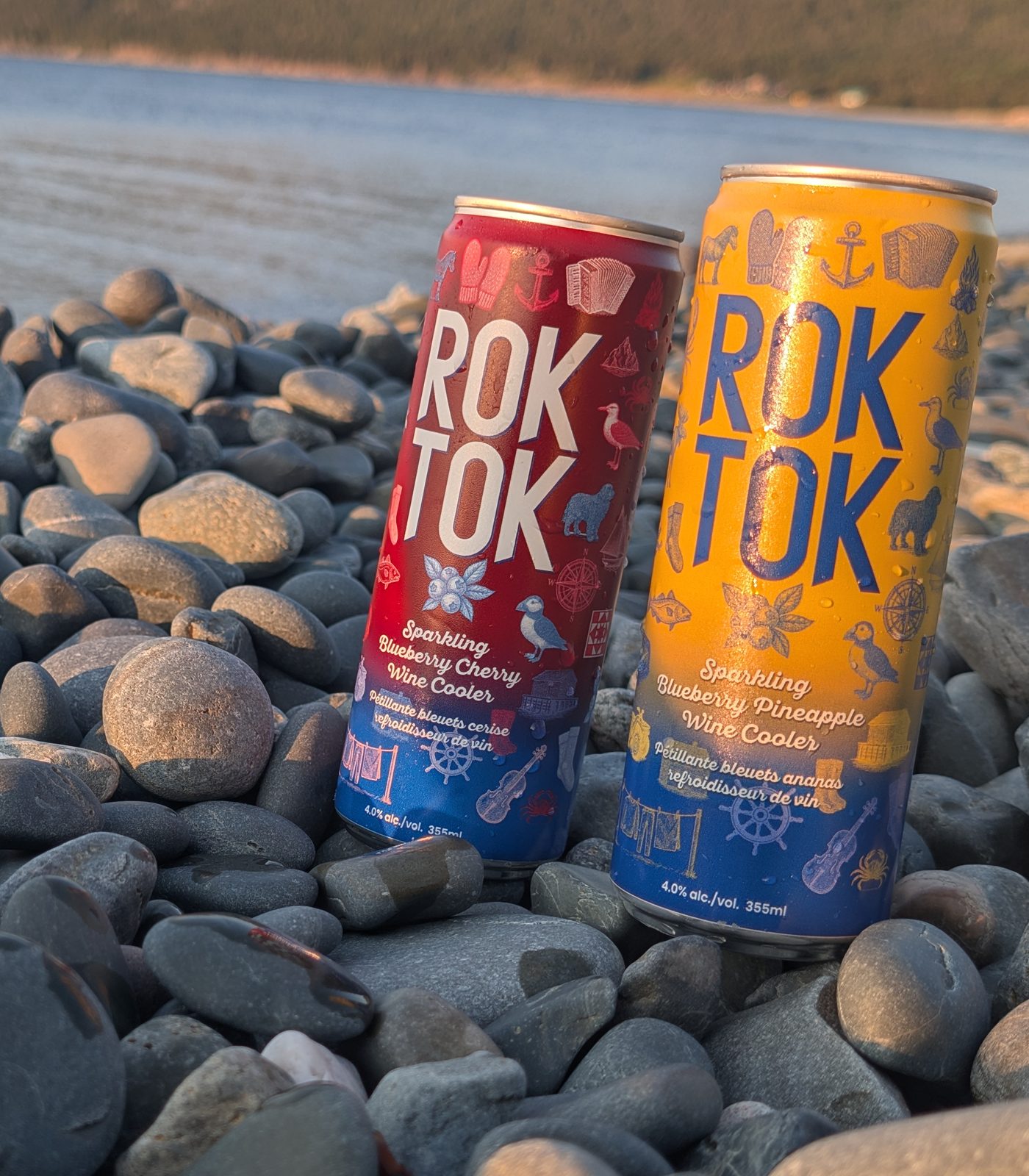 Two ROK TOK sparkling wine cooler cans standing on beach rocks by the water in Newfoundland